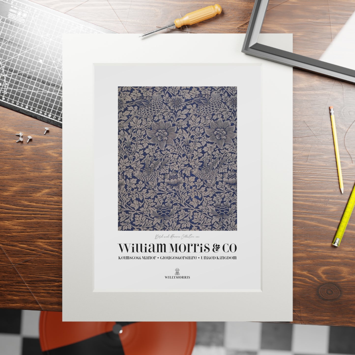 Framed patterned print with 'William Morris & Co' branding on a wooden table.