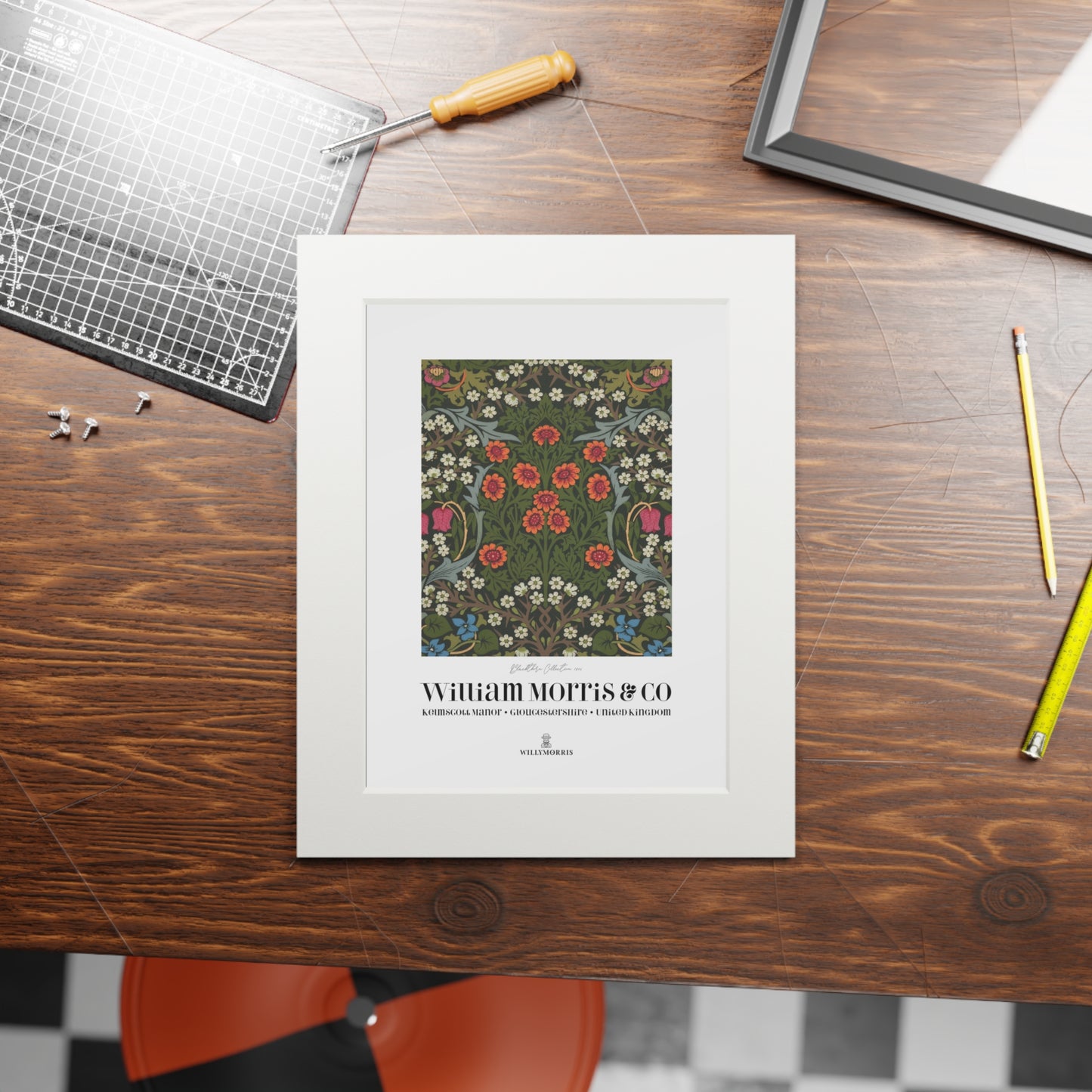 Framed artwork with 'William Morris & Co' on a wooden table with tools.