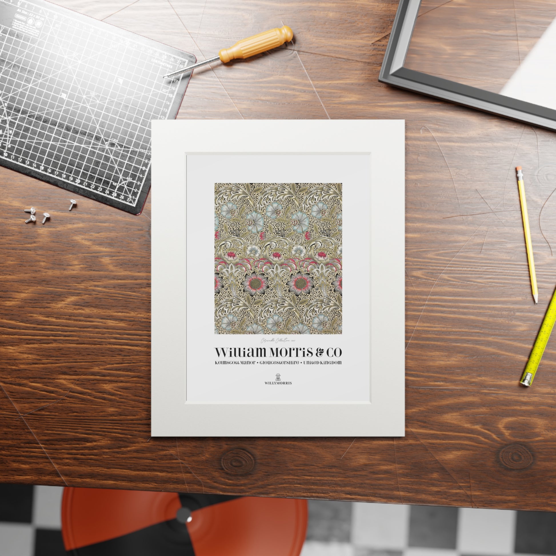 Framed artwork with 'William Morris & Co' design on a wooden table.
