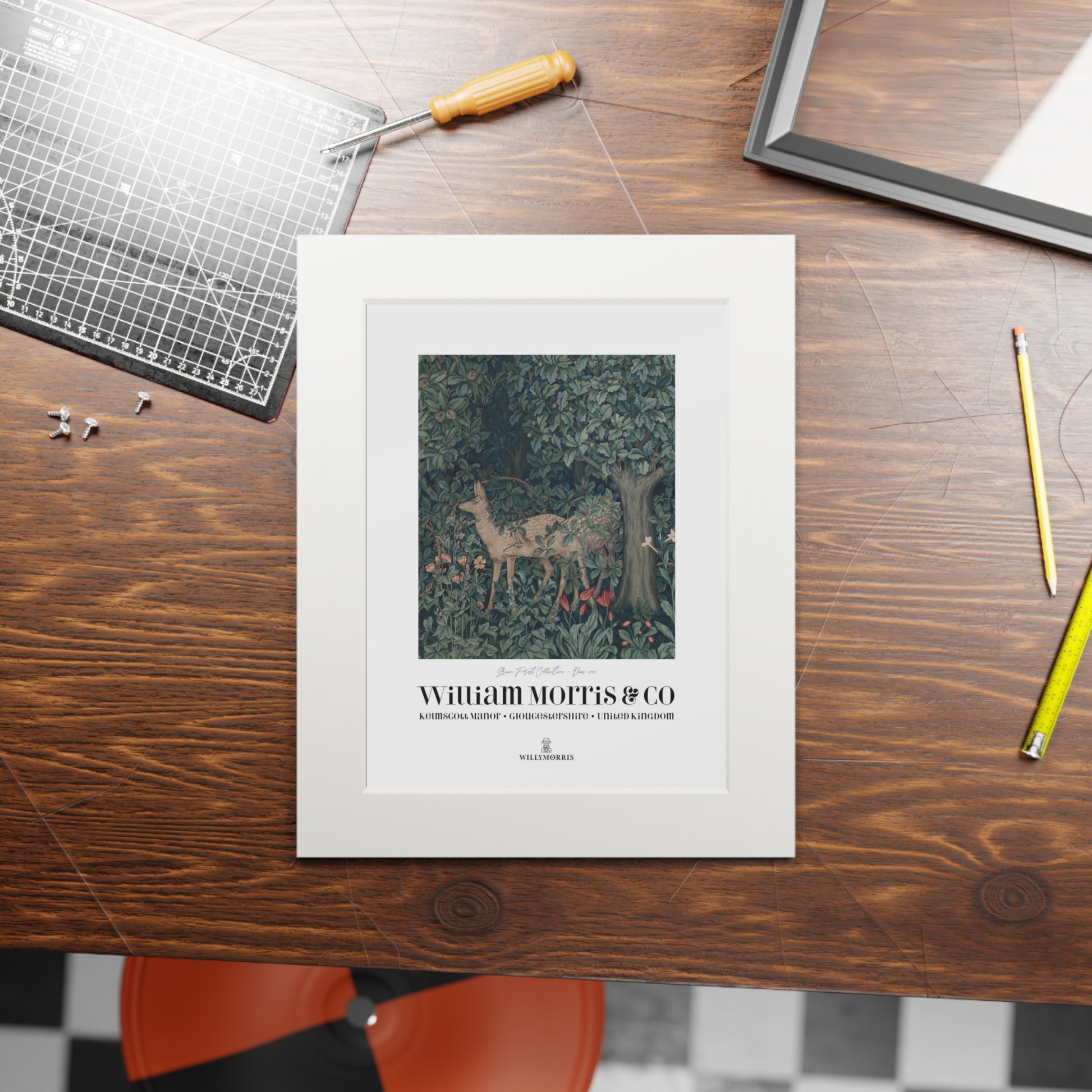 Framed artwork with 'William Morris & Co' on a wooden table with tools.