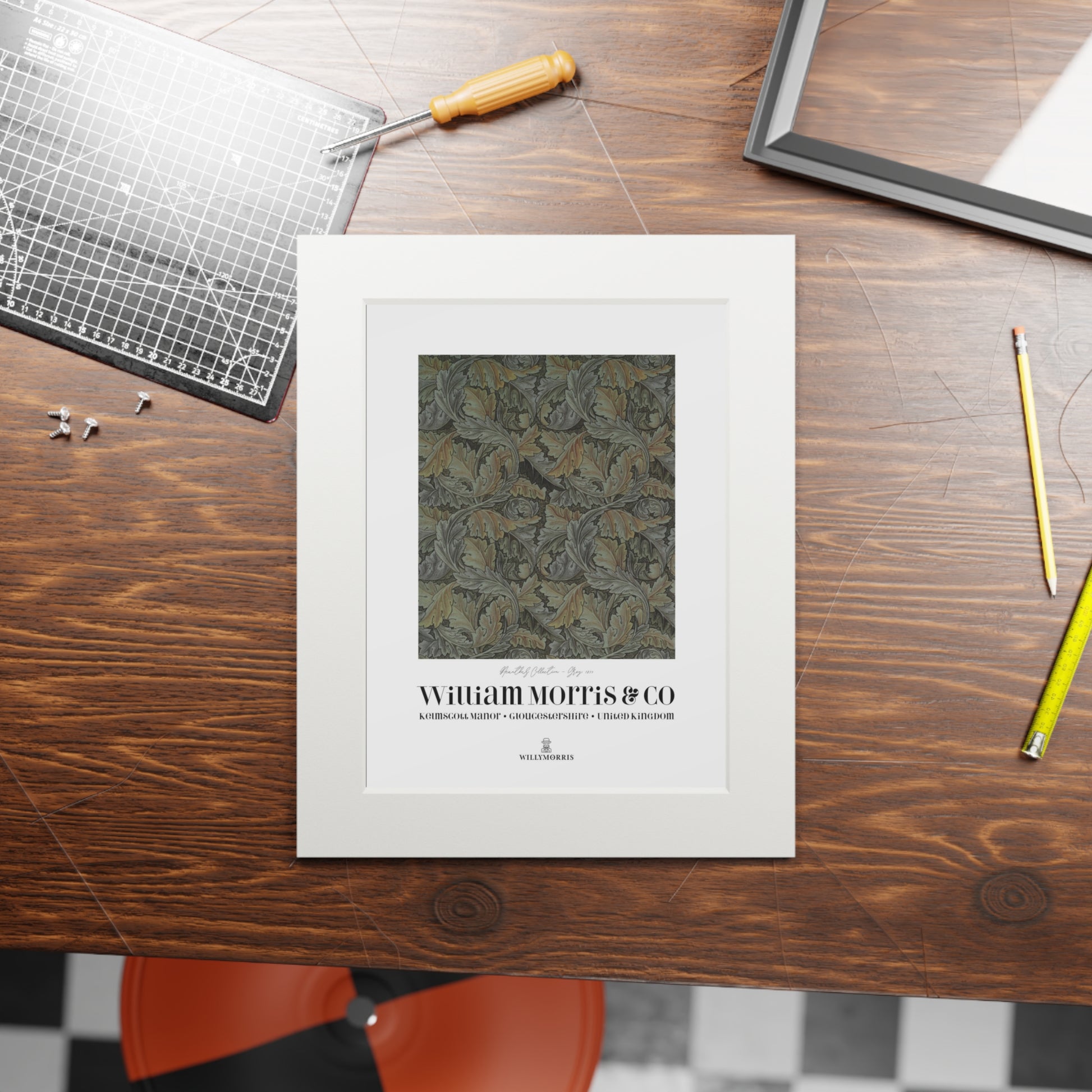 Framed artwork with 'William Morris & Co' on a wooden table with tools.