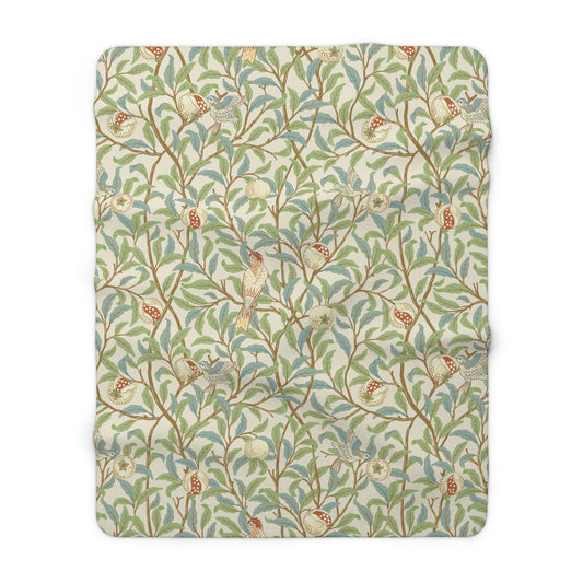 A plush fleece blanket with a floral William Morris & Co pattern featuring birds and pomegranates, predominantly in green tones.