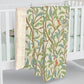 A plush fleece blanket with a floral William Morris & Co pattern featuring birds and pomegranates, predominantly in green tones.