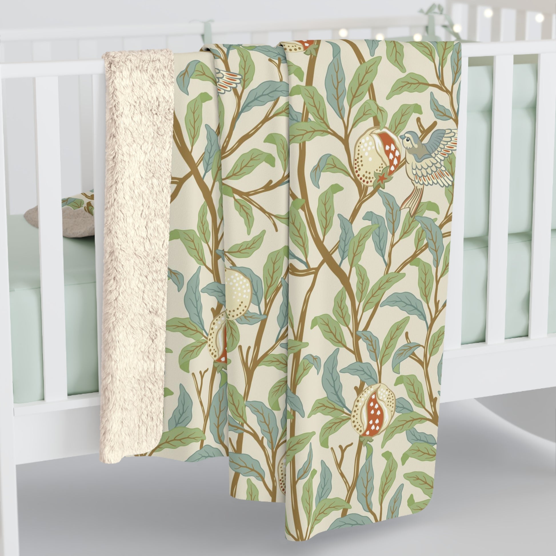 A plush fleece blanket with a floral William Morris & Co pattern featuring birds and pomegranates, predominantly in green tones.