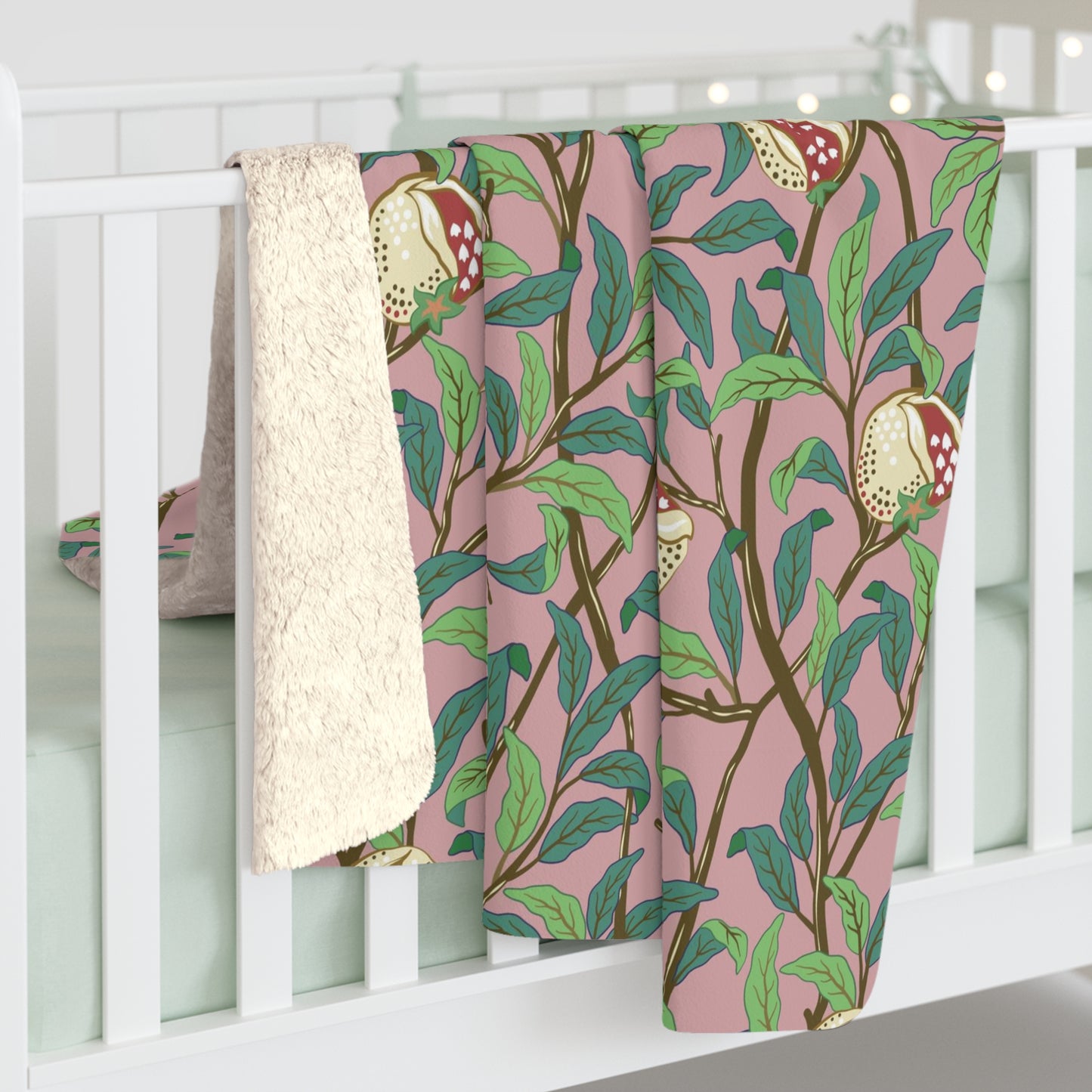 A plush fleece blanket with a floral William Morris & Co pattern featuring birds and pomegranate designs, predominantly in green and pink tones.