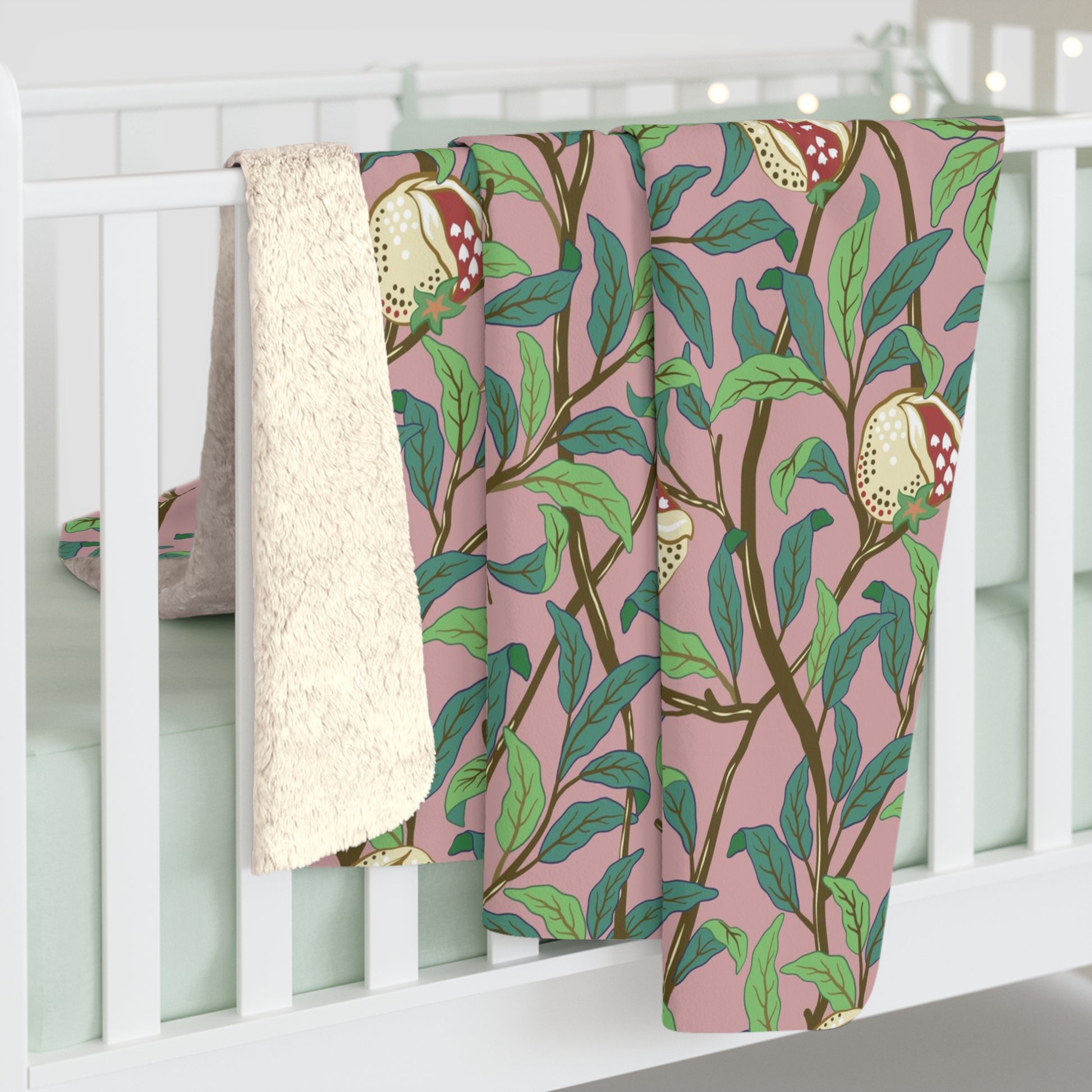 A plush fleece blanket with a floral William Morris & Co pattern featuring birds and pomegranate designs, predominantly in green and pink tones.
