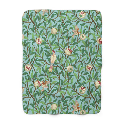 A Sherpa fleece blanket with an all-over print of birds and pomegranate fruits inspired by William Morris & Co on a blue background.