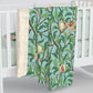 A Sherpa fleece blanket with an all-over print of birds and pomegranate fruits inspired by William Morris & Co on a blue background.