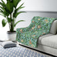 A Sherpa fleece blanket with an all-over print of birds and pomegranate fruits inspired by William Morris & Co on a blue background.