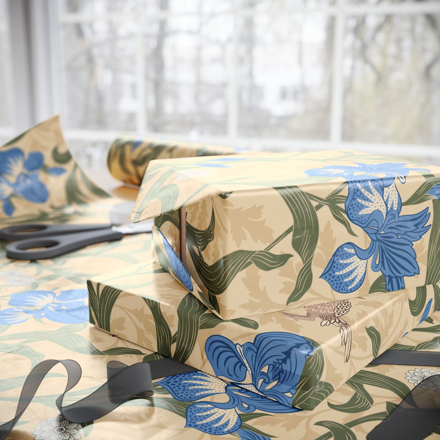 Gifts wrapped in decorative wrapping paper with William Morris & Co floral patterns, placed on a table alongside a roll of paper, scissors, and tags.