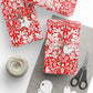 Gifts wrapped in red and white patterned paper with scissors and yarn on a gray surface.