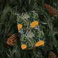 Patterned box with yellow flowers and green leaves on a background of pine needles and cones.