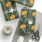 Gift wrap with yellow floral design on a white surface with scissors and twine.