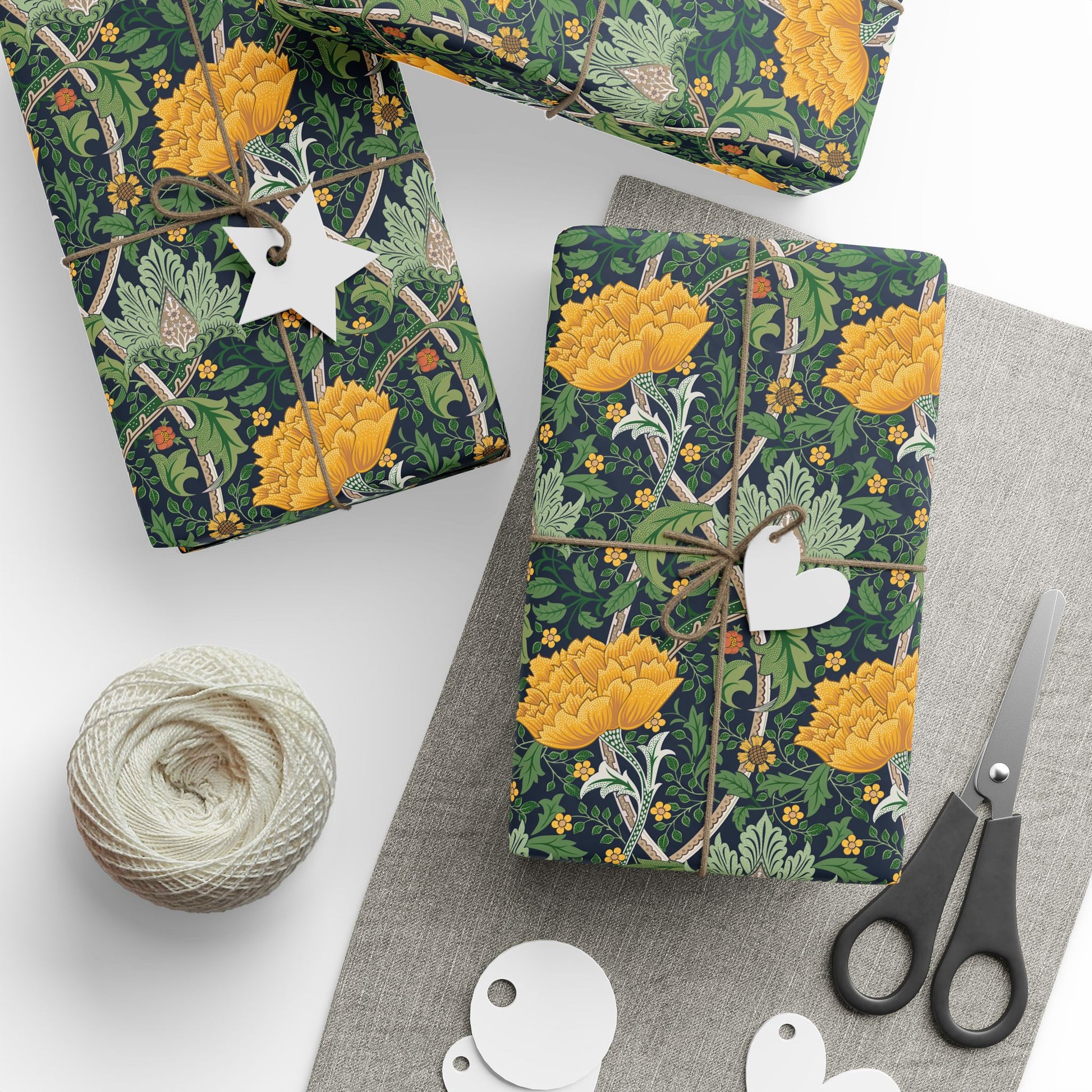 Gift wrap with yellow floral design on a white surface with scissors and twine.