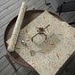 Floral-patterned wrapping paper with a roll of matching paper on a wooden surface.