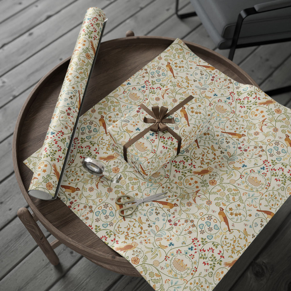Floral-patterned wrapping paper with a roll of matching paper on a wooden surface.
