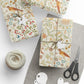 Gifts wrapped in decorative paper with a bird and floral pattern, accompanied by scissors and twine.