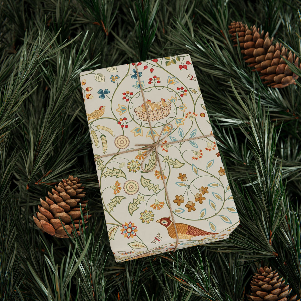 Decorative notebook with nature-themed design on green foliage with pine cones