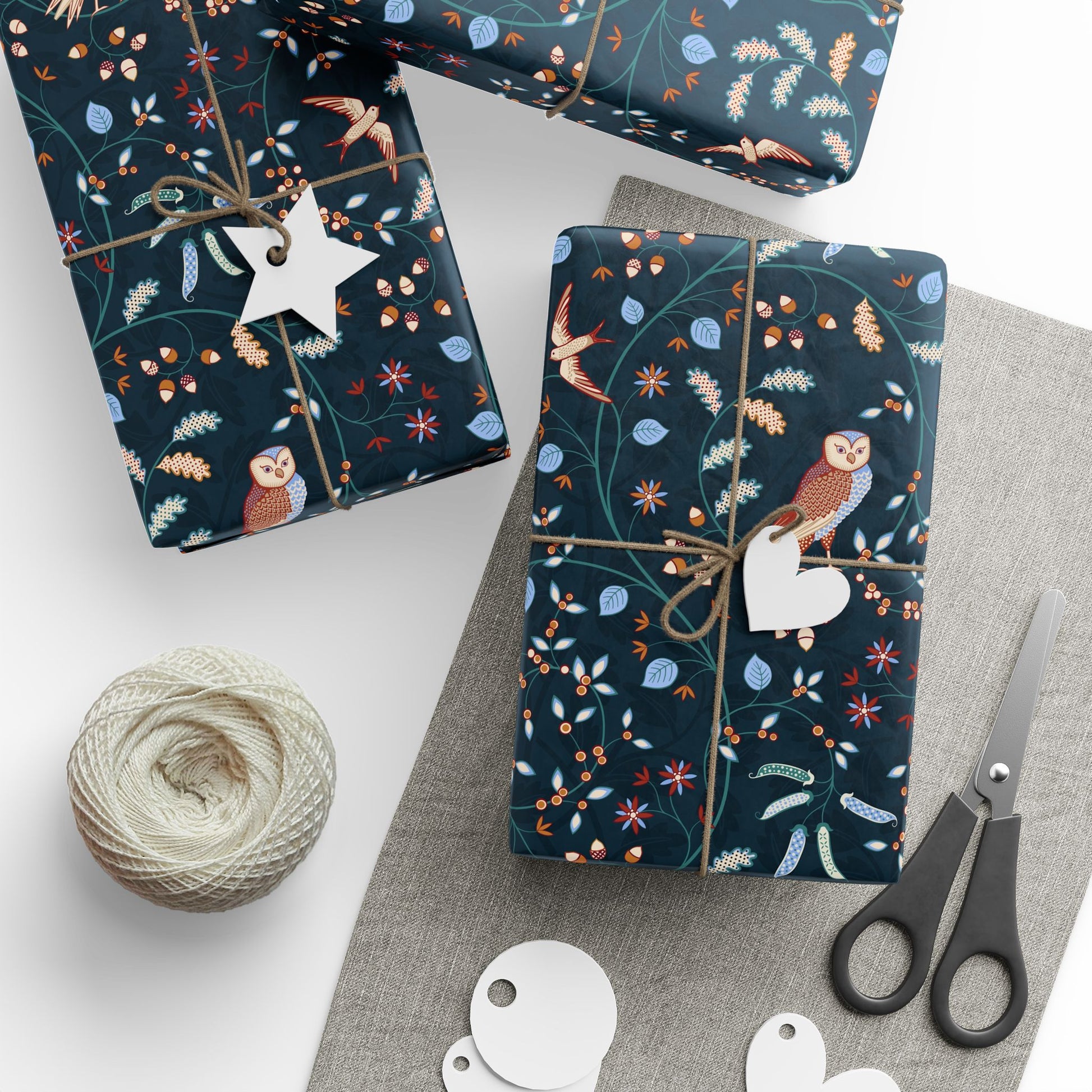 Gift wrap with owl and floral William Morris & Co pattern on a white surface with scissors and twine.