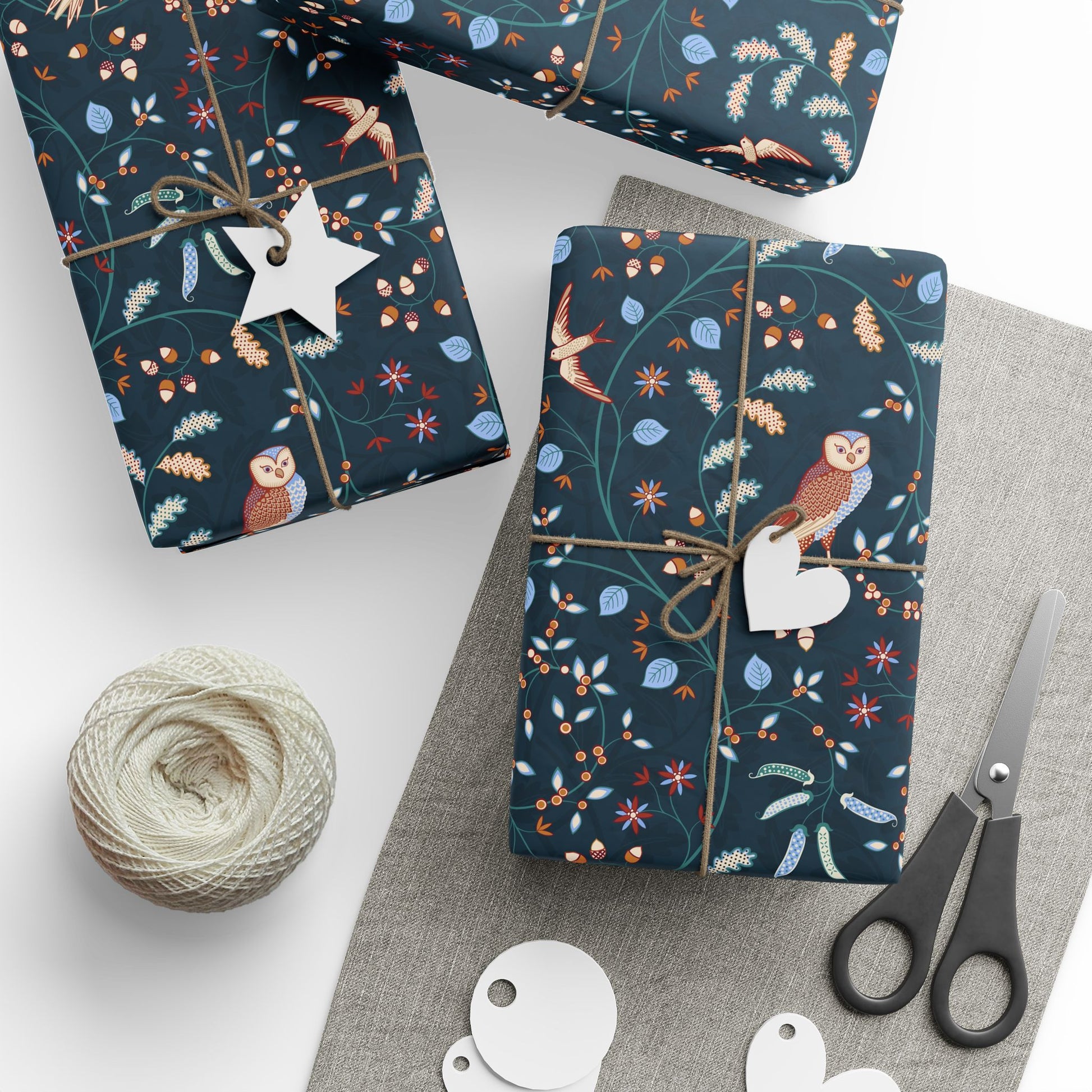 Gift wrap with owl and floral pattern on a white surface with scissors and twine.