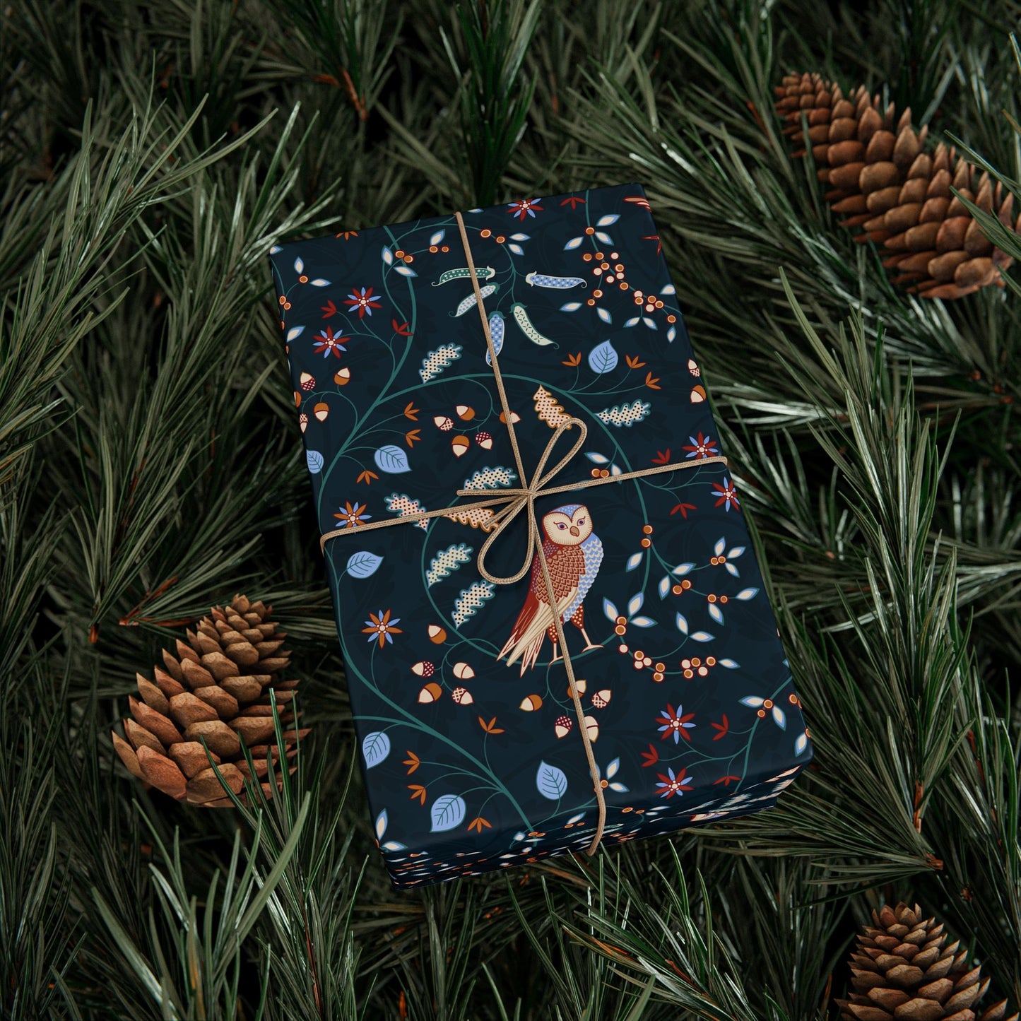 Gift wrapped in dark blue paper with owl design on pine branches