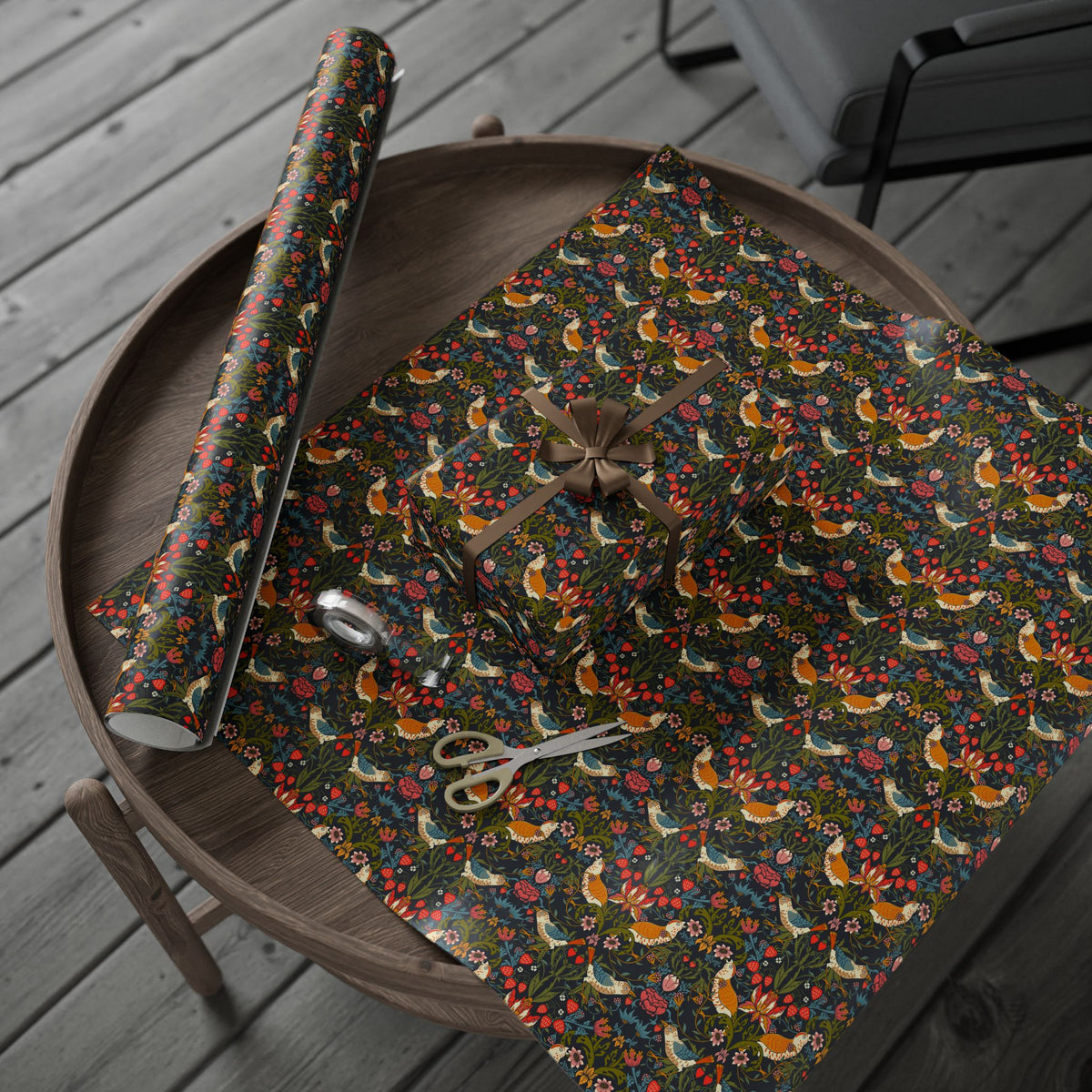 Floral-patterned fabric with scissors and fabric roll on a wooden surface