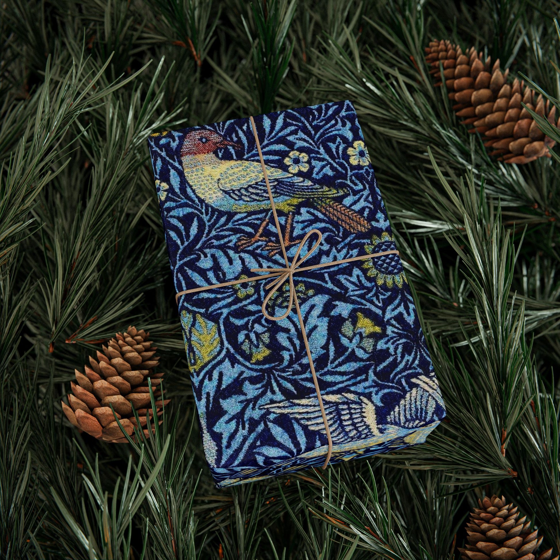 Blue patterned book tied with string on green foliage with pine cones