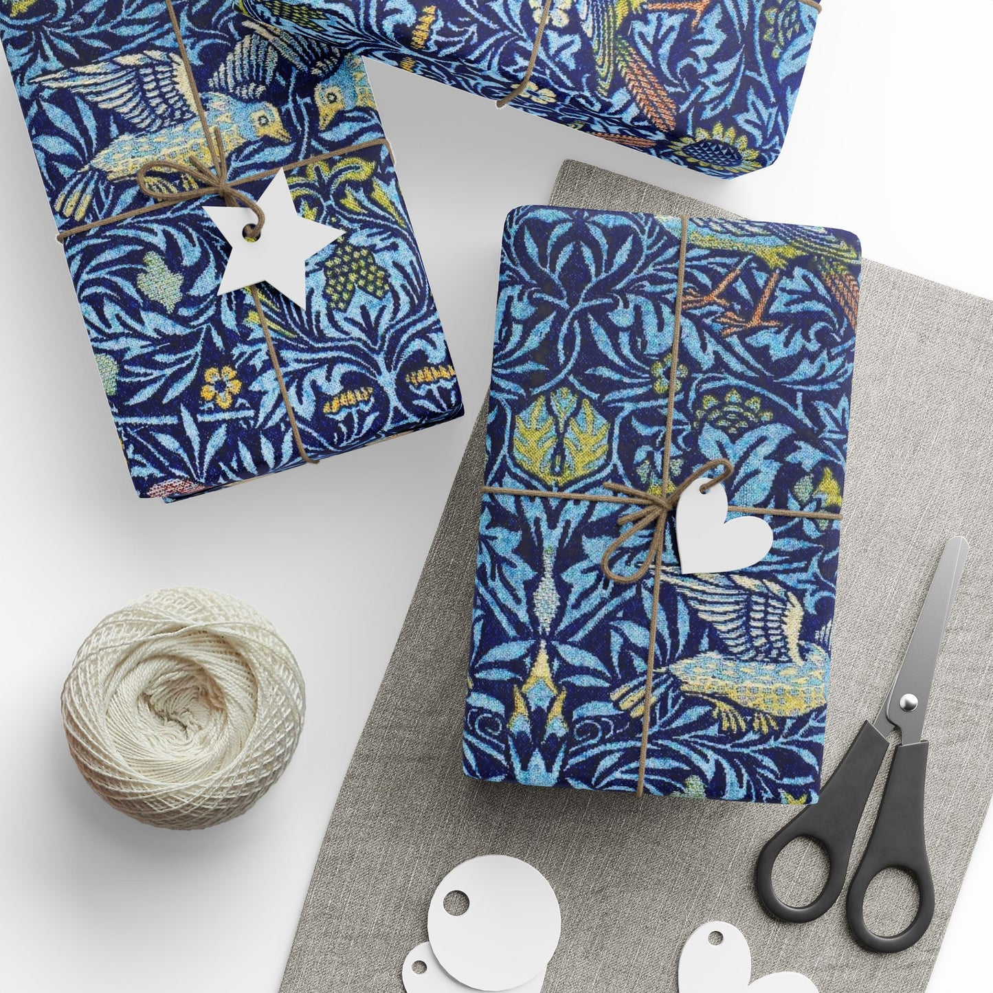 Gift-wrapped items with blue floral pattern, scissors, and yarn on a white surface