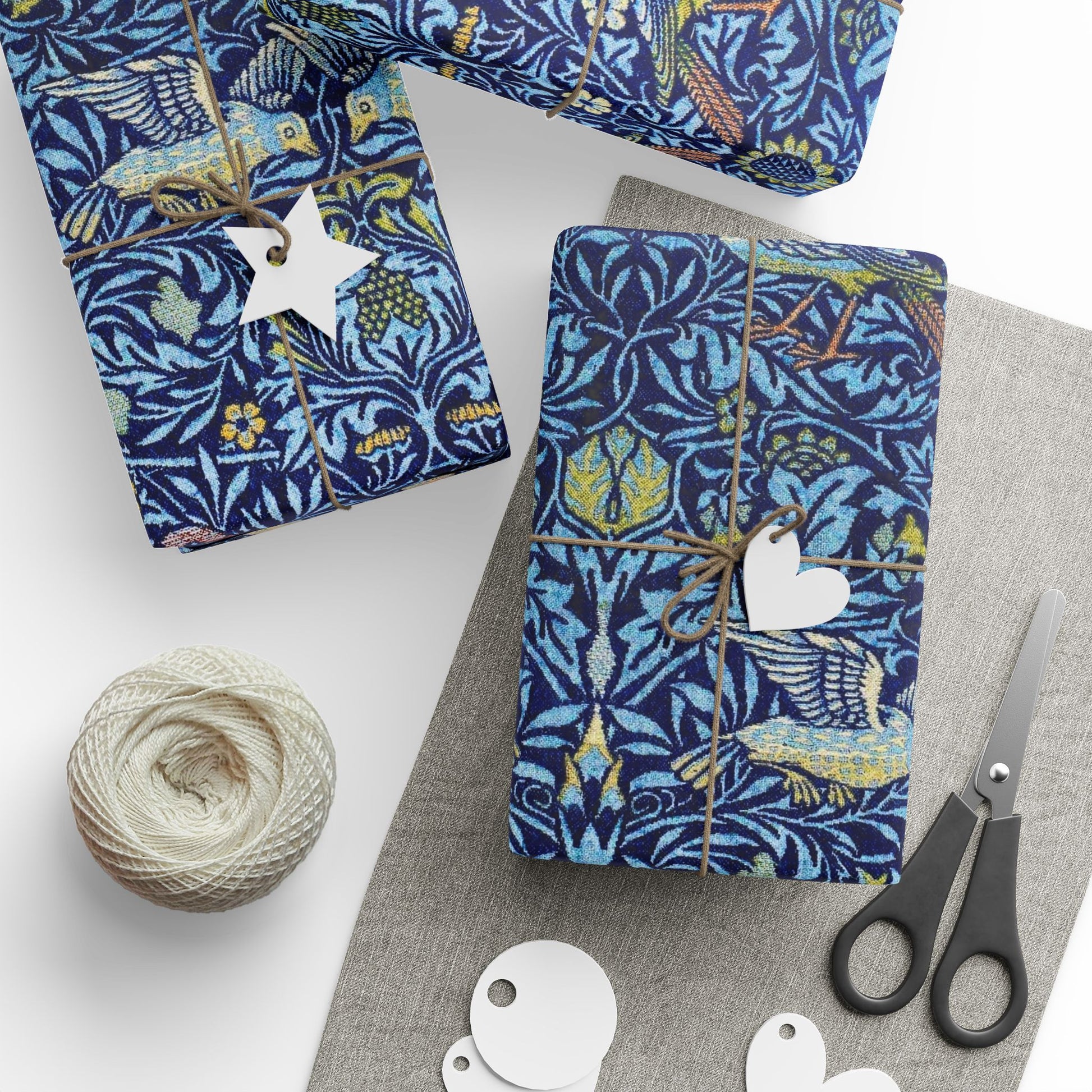 Gift-wrapped items with blue floral pattern, scissors, and yarn on a white surface