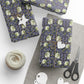 Gift wrap with floral pattern, scissors, yarn, and tags on a white surface