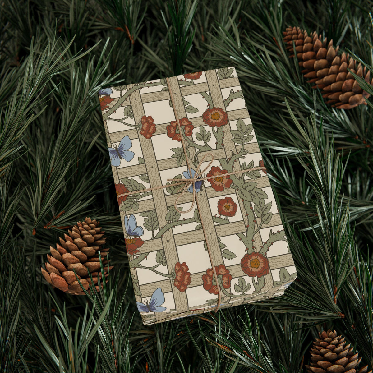Gift box with floral pattern on green foliage and pine cones