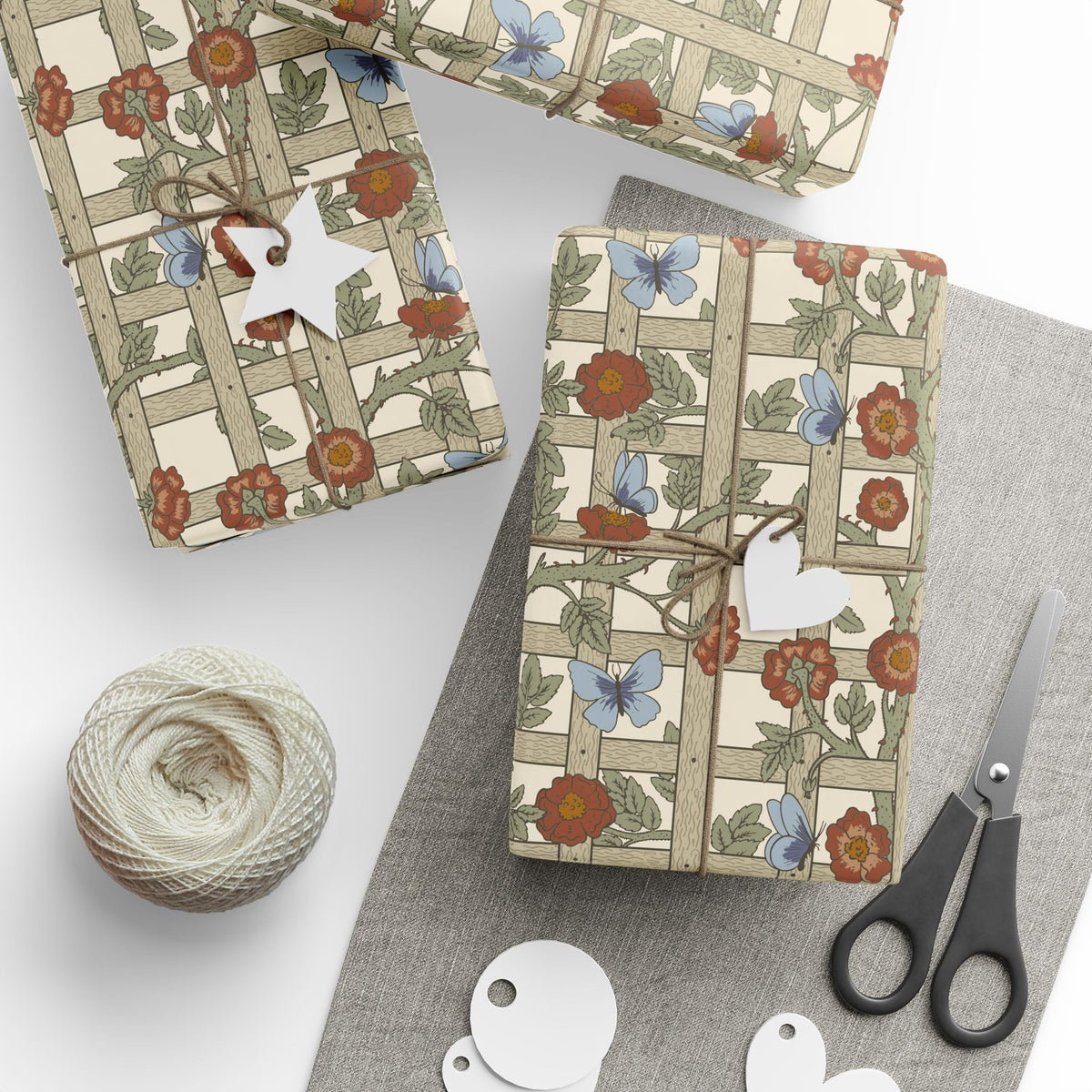 Gift-wrapped packages with floral pattern, scissors, and yarn on a white surface