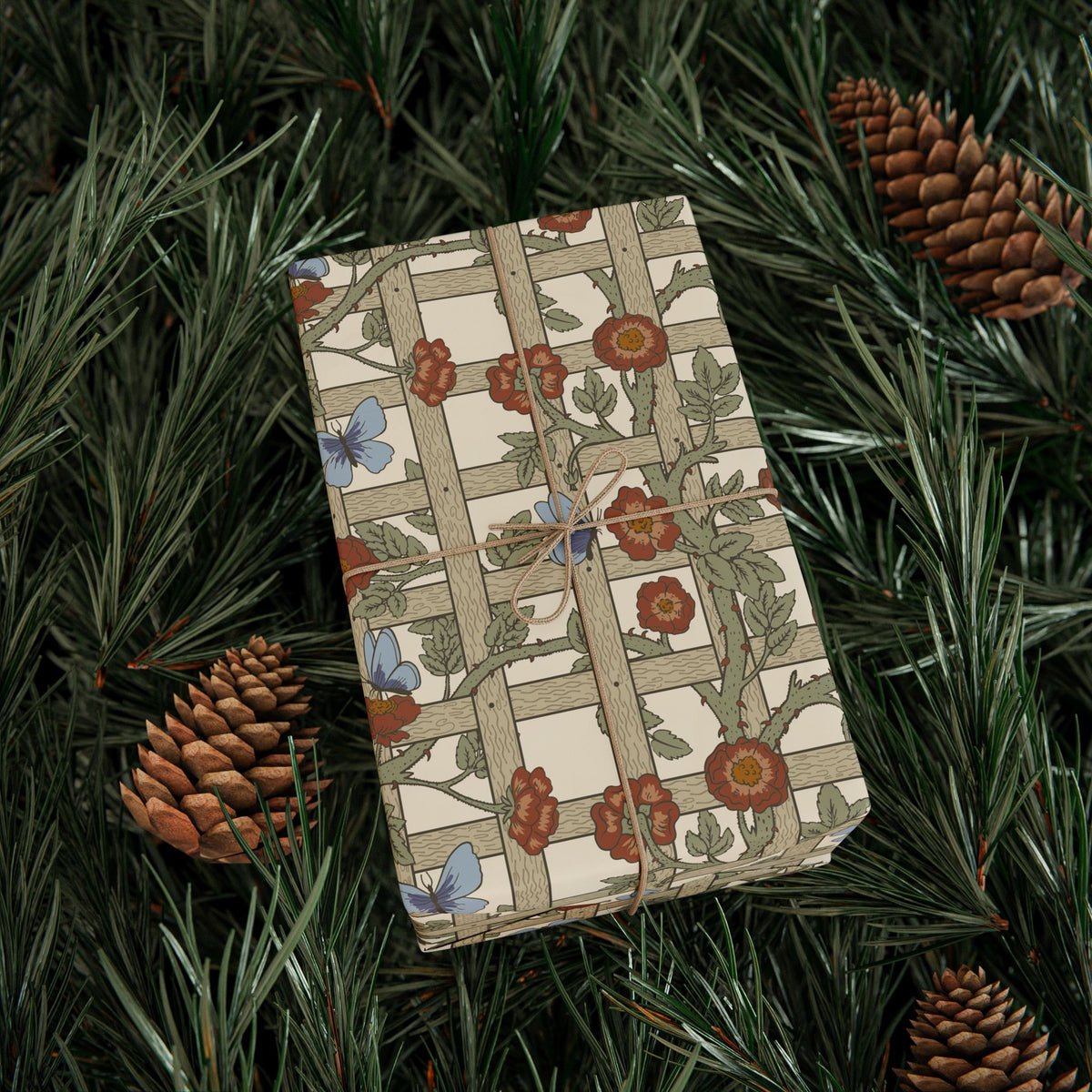 Gift box with floral pattern on green foliage and pine cones