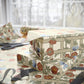 Floral-patterned gift box with ribbons on a table with scissors