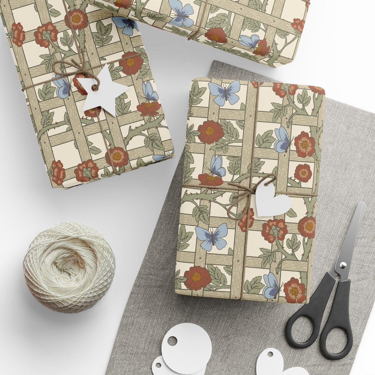 Gift wrap with floral pattern, scissors, twine, and tags on a white surface