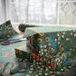 Gift box wrapped in floral-patterned paper with scissors on a matching tablecloth.
