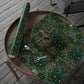 Roll of green floral-patterned wrapping paper on a wooden tray with scissors.