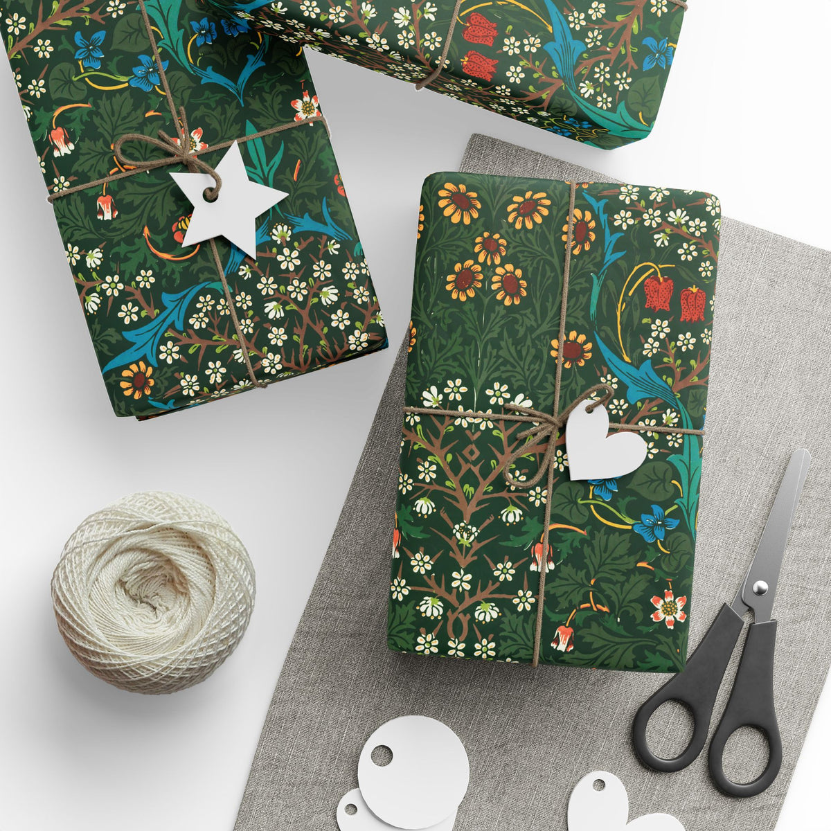 Gift boxes with floral patterns, tags, yarn, and scissors on a white surface