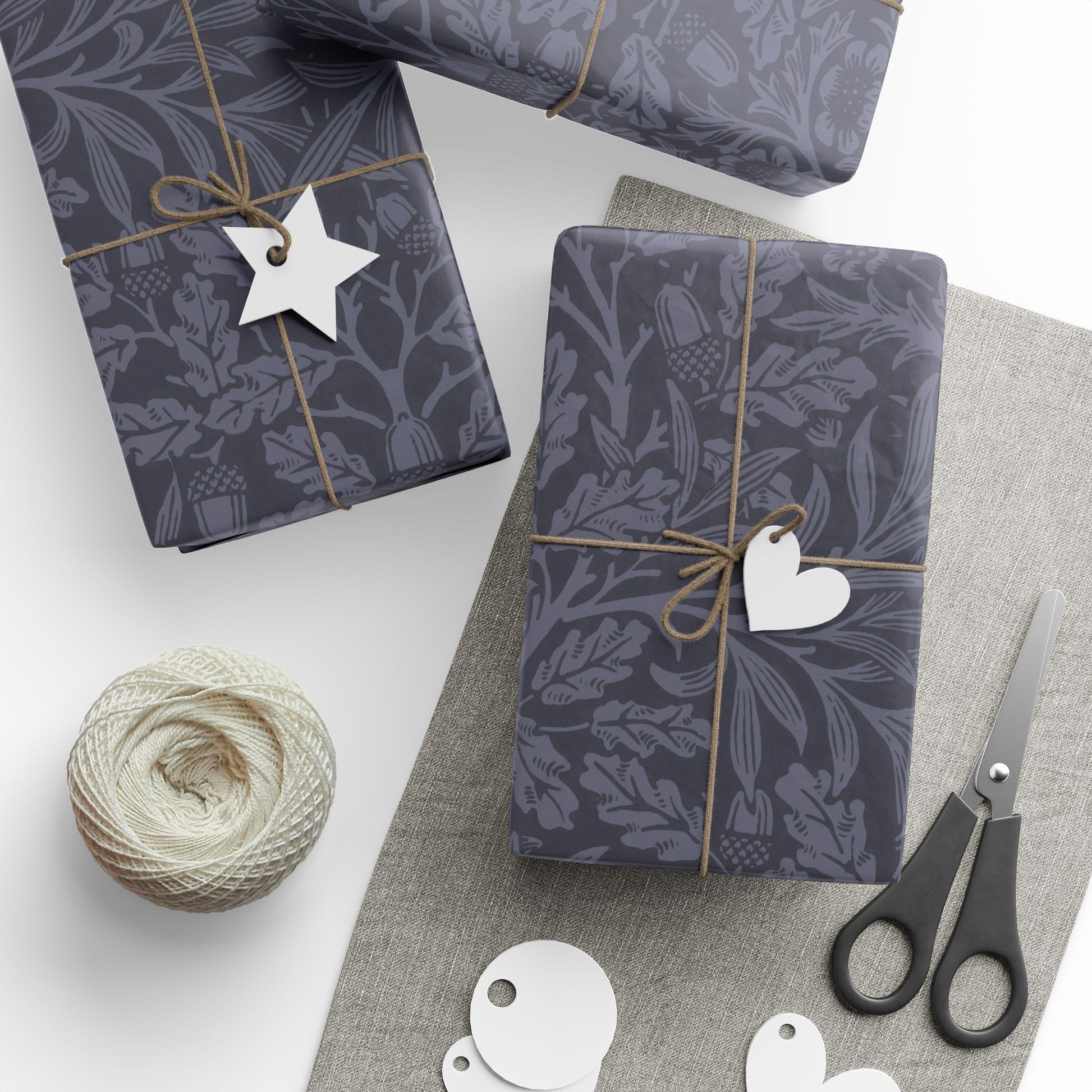 Gift boxes wrapped in dark blue patterned paper with decorative tags and scissors on a light surface.