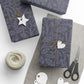 Gift boxes wrapped in dark blue patterned paper with decorative tags and scissors on a light surface.