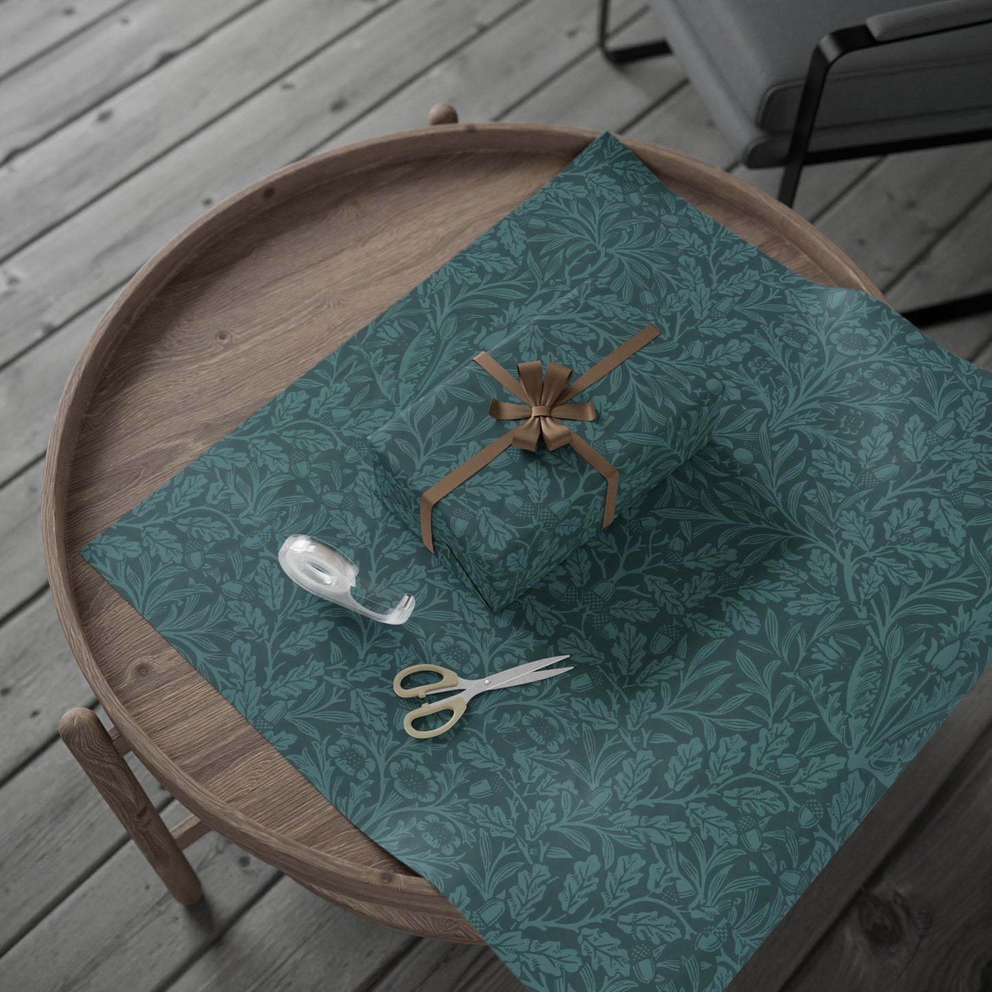 Teal patterned fabric with a rolled-up item, scissors, and a hook on a wooden surface.