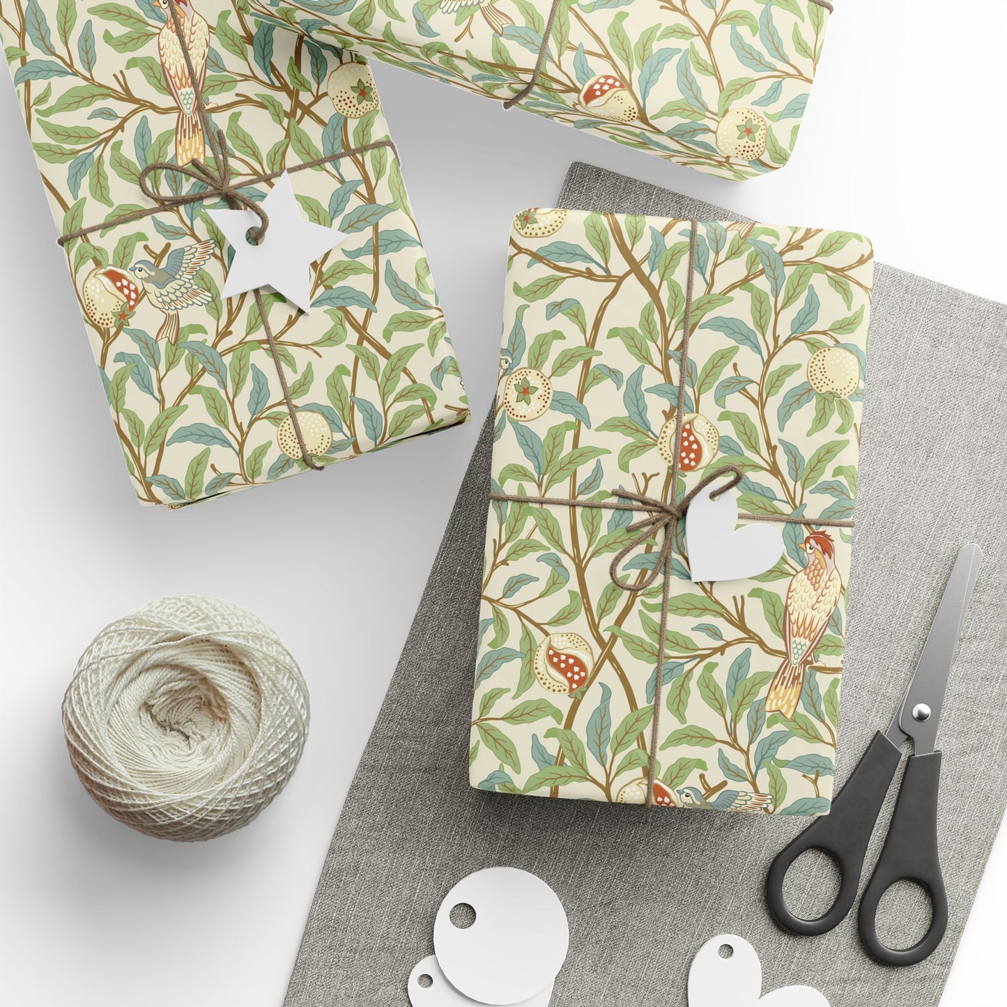 Gift boxes wrapped in decorative paper with birds and branches, accompanied by scissors and yarn.