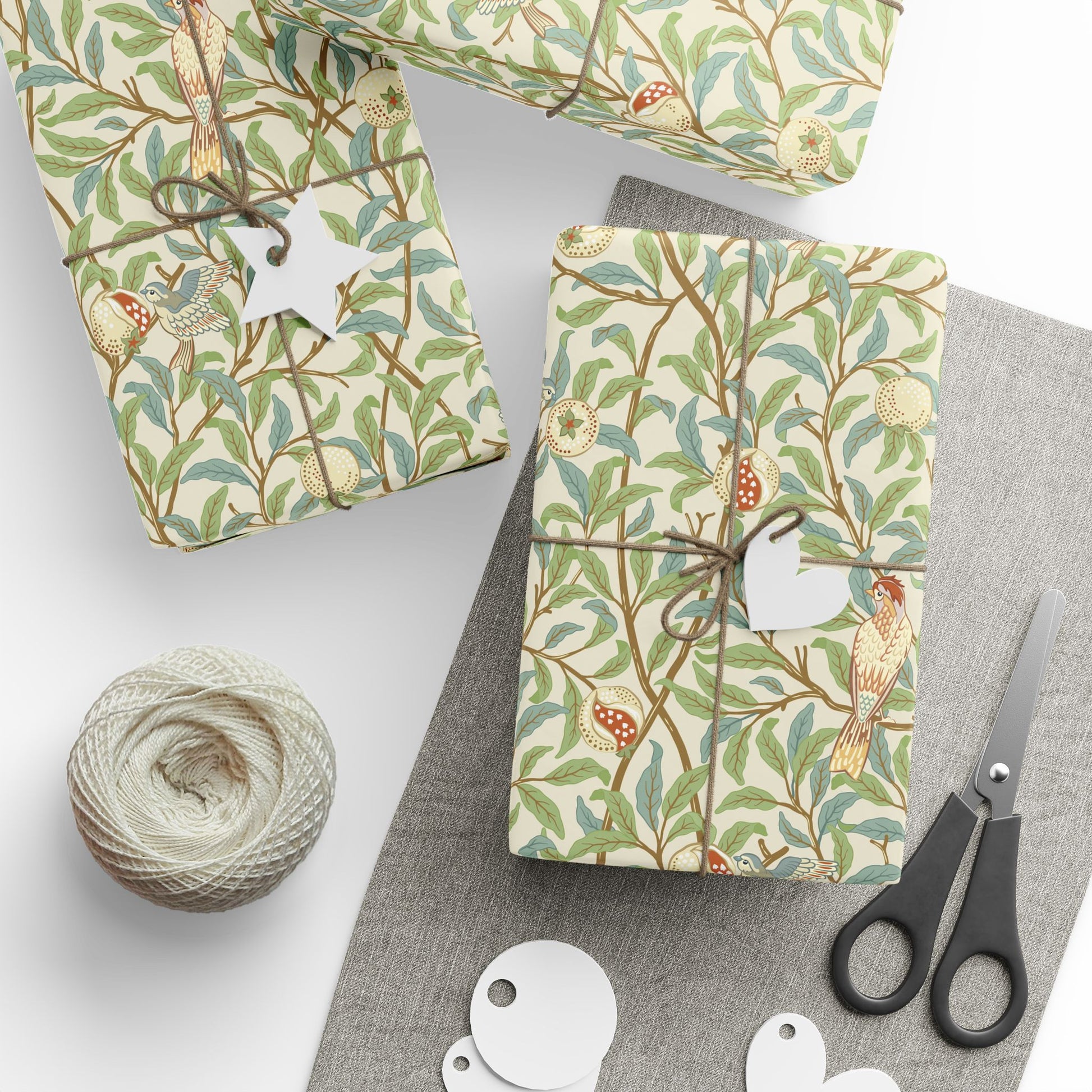 Gift boxes wrapped in decorative paper with birds and branches, accompanied by scissors and yarn.