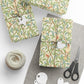 Gift boxes wrapped in decorative paper with birds and branches, scissors, and yarn on a white surface.