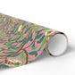 Roll of pink wrapping paper with green leaf pattern on a white background