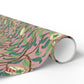 Roll of pink wrapping paper with green leaf pattern on a white background