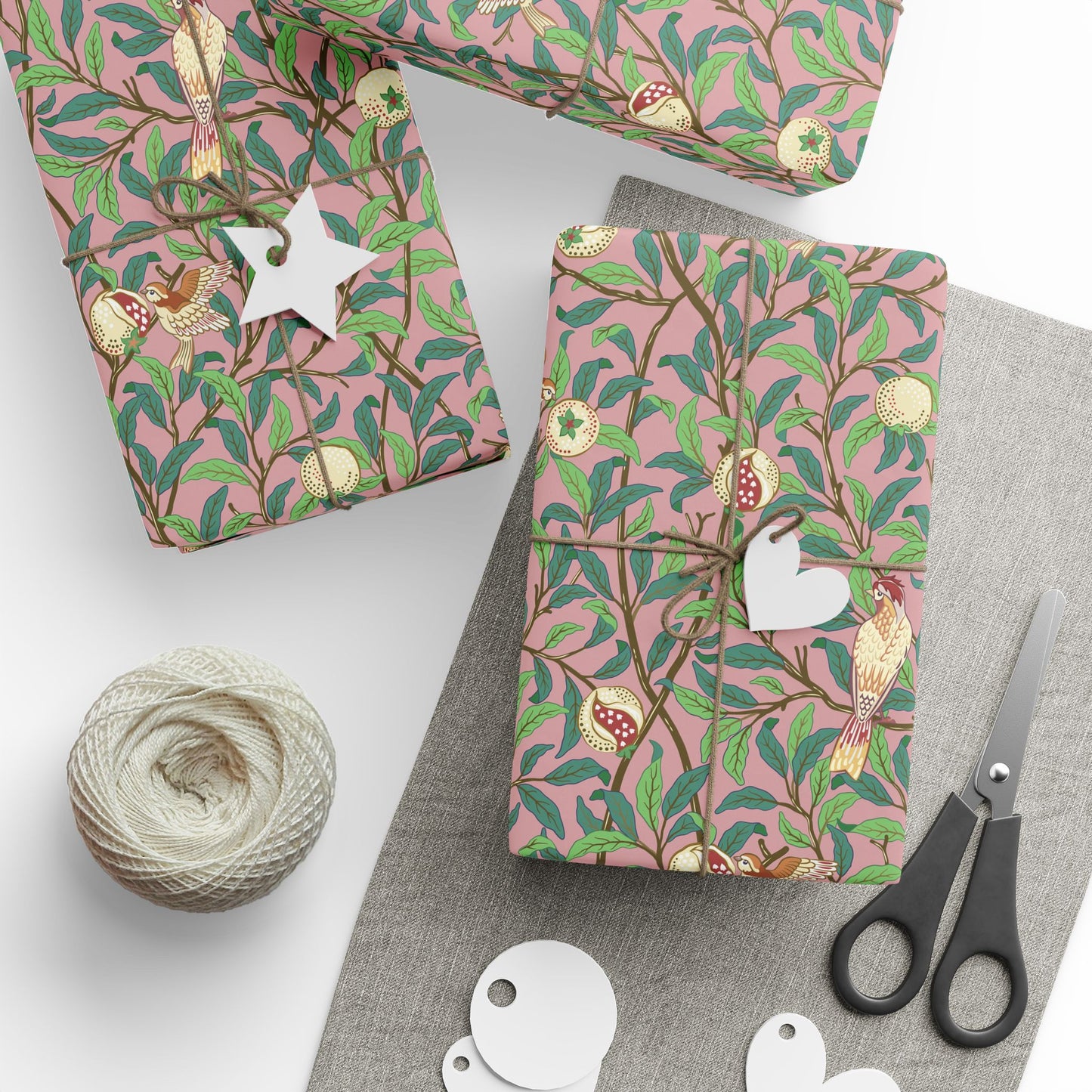 Gift boxes with pink floral pattern, scissors, and string on a white surface