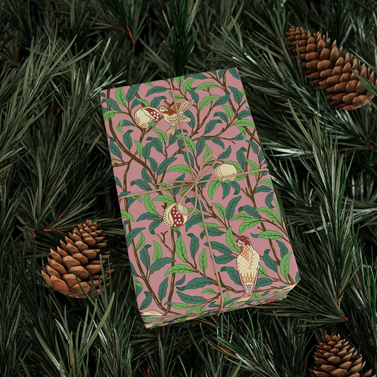 Pink notebook with nature-themed design on green leaves and pine cones