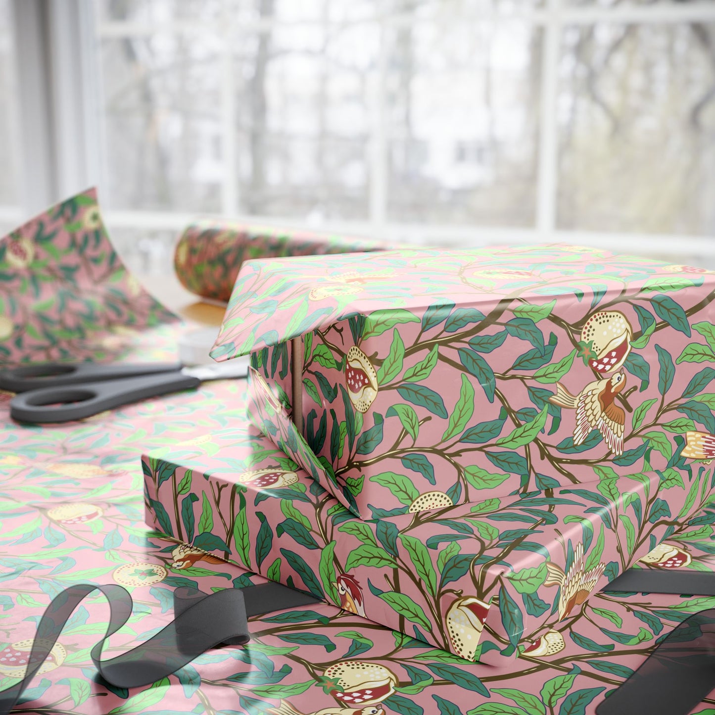 Gift boxes wrapped in pink paper with bird and leaf pattern on a table.