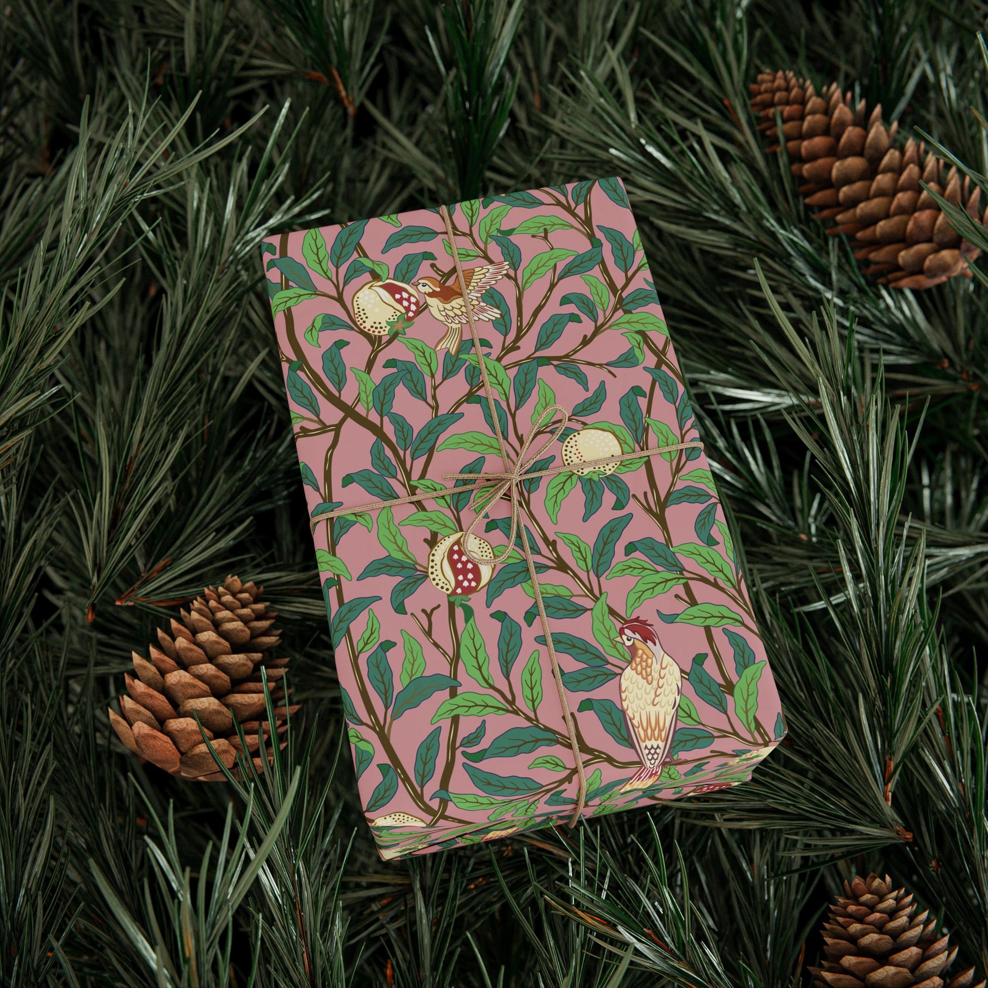 Pink notebook with nature-themed design on green leaves and pine cones